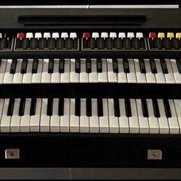 Černý dvoumanuálový synthesizér s dřevěnými bočními panely. Horní panel obsahuje řadu barevných tlačítek a posuvníků, vpravo na spodním panelu je náp…