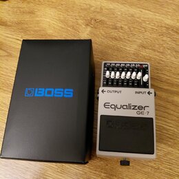 Bílý kytarový pedál s nápisy Equalizer GE-7 a logem BOSS. Horní panel obsahuje sedm posuvníků s označením 100, 200, 400, 800, 1.6k, 3.2k, 6.4k a Leve…