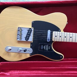 Světlé elektrické kytary typu Telecaster v tvrdém kufru s červeným polstrováním. Nástroj má světlý dřevěný povrch, černý pickguard a javorový hmatník…