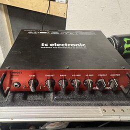 Černý basový zesilovač s červeným předním panelem. Na horní části je bílý nápis tc electronic a text DESIGNED AND ENGINEERED IN DENMARK. Na předním p…