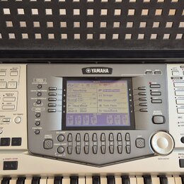 Digitální klavír značky YAMAHA s bílým šasi a černými klávesami. V horní části je umístěn displej s nápisem MAIN a různými ovládacími tlačítky rozděl…
