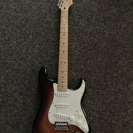 Elektrická kytara s tónem těla v provedení sunburst a světlým hřednicovým dřevě. Na hlavě je viditelné logo Fender. Kytara má bílý pickguard, tři sní…