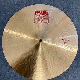 Zlatavý kovový činel s viditelným rýhováním povrchu. Na horní části je červené logo PAiste 2002 s nápisy TRADE MARK a MADE IN SWITZERLAND. V pravé čá…