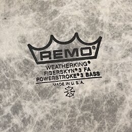 Detailní záběr na bílou bubnovou blánu s mramorovým vzorem. Uprostřed je černý nápis REMO v koruně a text WEATHERKING, FIBERSKYN 3 FA, POWERSTROKE 3…