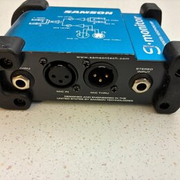 Modrý elektronický přístroj s černým plastovým rámem a nápisy SAMSON a S-monitor. Na zadní straně jsou konektory s popisky THRU, MIC IN, MIC THRU a S…