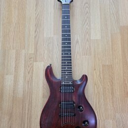 Elektrická kytara s tmavě hnědým dřevěným povrchem a černým hmatníkem. Na hlavě je viditelné logo "Schecter". Nástroj má jeden humbucker v pozici kob…