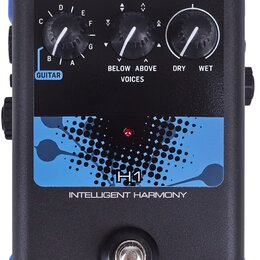 Černý efektový pedál s modrými prvky a nápisem TC HELICON. Na horní straně jsou tři otočné ovladače s popisky GUITAR (označení A až G), VOICES (BELOW…