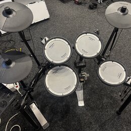 Elektronická bicí souprava značky Roland v černé barvě. Na čelech padů a na činelech je vidět logo Roland, u padů jsou dále nápisy V-Drums a V-Drum.…