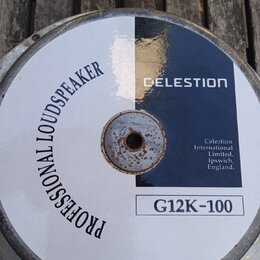 Zadní strana reproduktoru s bílým a tmavě modrým povrchem. Je na ní nápis PROFESSIONAL LOUDSPEAKER a značka CELESTION s označením modelu G12K-100. V…