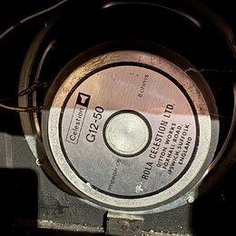 Fotografie zachycuje zadní stranu reproduktoru s kovovým magnetem. Na středovém štítku je uveden název Celestion G12-50 a impedance 8 ohms. Kolem stř…