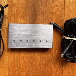 Stříbrný zdroj napájení s nápisy „Harley Benton“, „POWERPLANT ISO-5 PRO“ a „ISOLATED OUTPUTS POWER SUPPLY“. Zařízení má pět výstupů s označením „12V…