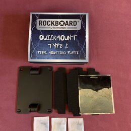 Fotografie zobrazuje sadu pro montáž pedálů v originálním krabici. Na krabici je nápis ROCKBOARD® by WARWICK, QUICKMOUNT TYPE C PEDAL MOUNTING PLATE.…