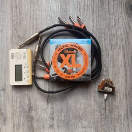 Sada příslušenství složená z bílého ladičky KORG CA-2, balení strun D'Addario XL EXL110 NICKEL WOUND 10-46, černého kabelu s několika konektory a mal…