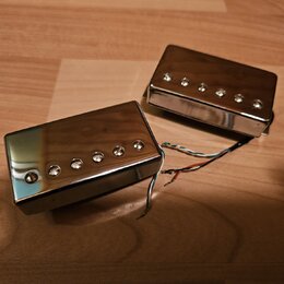 Dva elektrické snímače typu humbucker s chromovaným kovovým krytem. Snímače mají viditelné šestiky pólů a z jejich boku vedou barevné připojovací vod…