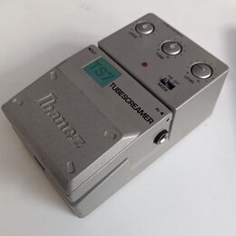 Stříbrný efekt pedál s kovovým šasi. Na horní části je nápis Ibanez, zelený štítek s označením TS7 a černý nápis TUBESCREAMER. Ovládací panel obsahuj…