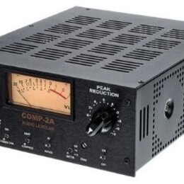 Černý rackový procesor s nápisem COMP-ZA AUDIO LEVELER. Na předním panelu se nachází analogový VU metr, dva otočné ovladače s popisky GAIN a PEAK RED…