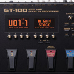 Černý kytarový procesor Boss GT-100 Guitar Amp Effects Processor. Zařízení má digitální displej s nápisem U01-1 a Hi Gain Stack, několik ovládacích k…