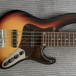 Elektrická basová kytara s korpusem v barevném přechodu od žluté přes oranžovou k hnědé a černé. Nástroj má tmavě hnědý pickguard s texturou želvy a…