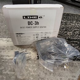 Bílá krabice s nápisy LINE 6, DC-3h a 9V DC POWER SUPPLY (EU/UK). Před krabicí je v plastovém obalu černý síťový adaptér a přívodní kabel. Na štítku…