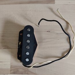 Černý elektrický kytarový snímač s pěti viditelnými kovovými póly. Snímač má připojené černé a bílé vodiče. Na povrchu nejsou žádné viditelné značky…