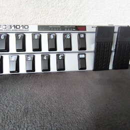 Šedý MIDI kontrolér s nápisem FCB1010 MIDI FOOT CONTROLLER. Zařízení obsahuje dvě řady černých spínacích pedálů s bílými čísly 1 až 10 a tlačítky UP…
