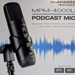 Fotografie znázorňuje krabici s černým kondenzátorovým mikrofonem. Na obalu je uveden název značky marantz PROFESSIONAL a model MPM-4000U PODCAST MIC…