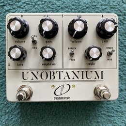 Bílý kytarový efekt s nápisem UNOBTANIUM a logem crazy tube circuits. Zařízení má osm ovládacích knobů s popisky volume, gain, volume, gain, tone, em…
