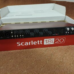 Černý rackový zvukový rozhraní umístěný v původním červenobílém obalu. Na přední straně zařízení je nápis Scarlett 18i20 a logo Focusrite. Přístroj o…