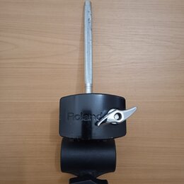 Černý držák s kovovou tyčí a utahovacími knoflíky. Na černém plastovém těle je svisle napsáno logo Roland. Kovová tyč vykazuje známky opotřebení a po…