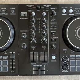 Černý DJ set tvořený dvěma kontrolérymi a centrálním mixérem. Na středovém panelu jsou nápisy PERFORMANCE CONTROLLER DDJ-400, rekordbox a Pioneer DJ.…