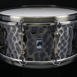 Kovový snare drum s tmavým, kovem vypracovaným povrchem v kladeném vzoru. Uprostřed korpusu je logo s panterem a nápisem BLACK PANTHER. Na horním obr…