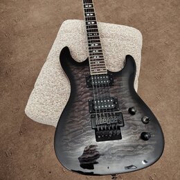Černá elektrická kytara s výraznou strukturou dřeva na topu. Na hlavě hmatníku je viditelné logo PRS. Nástroj má dva humbuckery, prohýbatelný most a…