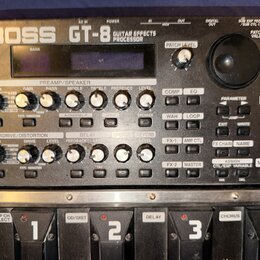 Černý kytarový procesor Boss GT-8 Guitar Effects Processor. Zařízení obsahuje displej, početné otočné knoflíky a tlačítka s nápisy jako PREAMP/SPEAKE…