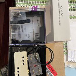 Sada snímačů v průhledném plastovém boxu a bílé krabici s nápisem „CUniFe™ WIDE RANGE JAZZMASTER™ PICKUP SET“. V boxu jsou dva krémové snímače, jeden…