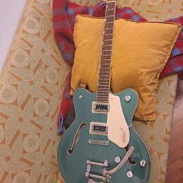 Polodupatá elektrická kytara v tyrkysové barvě s bílým bindingem a krčkem z tmavého dřeva. Na hlavě je nápis Gretsch, na pickguardu je logo GRETSCH a…