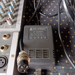 Černý síťový adaptér značky PHONIC s bílým štítkem. Na štítku je text: AC ADAPTOR, P/N: 353-21904-000-0, INPUT: 230V AC 50Hz, OUTPUT: 16.8Vx2 AC 1A a…