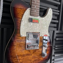 Elektrická kytara typu Telecaster s hnědým slunečním odstínem (sunburst) a výraznou plamenovitou strukturou dřeva. Nástroj má perleťový pickguard a h…