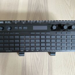 Černý polysequencer s nápisy KORG a SQ-64 POLY SEQUENCER. Zařízení obsahuje mřížku šedých tlačítek, několik otočných ovladačů a malý displej. Na horn…