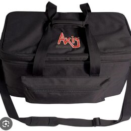 Černá textilní taška s dvěma rukojetmi a ramenním popruhem. Na přední horní části je červenobílé logo Axis a pod ním nápis PERCUSSION. Taška má v hor…