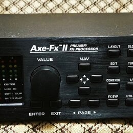 Černý rackový procesor s nápisy FRACTAL AUDIO SYSTEMS a Axe-Fx II PREAMP/ FX PROCESSOR. Na předním panelu je displej, ovládací knoflíky a tlačítka s…