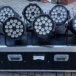 Deset černých LED PAR reflektorů umístěných na černém transportním case s hliníkovými hranami a kovovými zámky. Case má dvě madla a vprostřed malý bí…