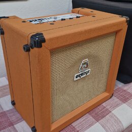 Kytarový kombozesilovač v oranžovém vinylu s béžovou textilní maskou. Na přední straně je bílý obdélníkový štítek s nápisem ORANGE a nad ním malý bar…