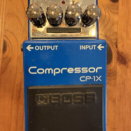 Modrý efekt pedál s nápisy Compressor a CP-1X. Na spodní části je černý gumový spínač s vyraženým logem BOSS. Horní ovládací panel obsahuje čtyři chr…