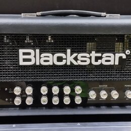 Černý kytarový zesilovač s kovovou mřížkou, na které je bílý nápis Blackstar. Přední panel obsahuje řadu ovládacích knoflíků a přepínačů s popisky ja…