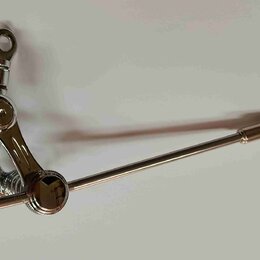 Stříbrný kovový mechanismus tremola s páčkou. Na konci rotující části je vyryté písmeno „B“. Povrch je lesklý a v dobrém stavu.
