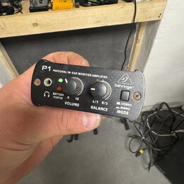 Černý osobní sluchátkový zesilovač s nápisem P1 PERSONAL IN-EAR MONITOR AMPLIFIER a logem behringer. Zařízení má dva ovládací knofíky s popisky VOLUM…