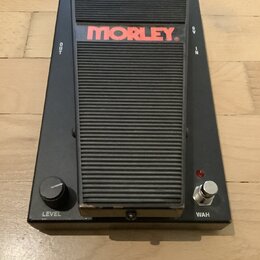 Černý wah pedál značky MORLEY s žebrovaným povrchem šlapací plochy. Na horní části je červené logo MORLEY a nápisy OUT, IN a 9V. V dolní části se nac…