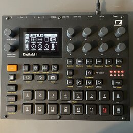Černý sampler Digitakt II s displejem a řadou ovládacích prvků. Na přístroji jsou viditelná tlačítka, otočné knoflíky a v pravém horním rohu logo Ele…