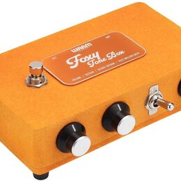 Kytarový efekt pedál v oranžovém textilním potahu. Na horní straně je kovový štítek s nápisy „WAARM“, „Foxy Tone Box“ a „VOLUME / SUSTAIN / OCTAVE SU…