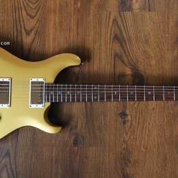 Žlutá elektrická kytara s tmavým hmatníkem a dvěma humbuckery. Na hlavě nástroje je viditelné logo Epiphone. Tělo má tři červené oválné knofíky a stř…